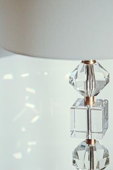 Gold and crystal details of a bedside lamp with shadows at sunset, luxury home decor closeup