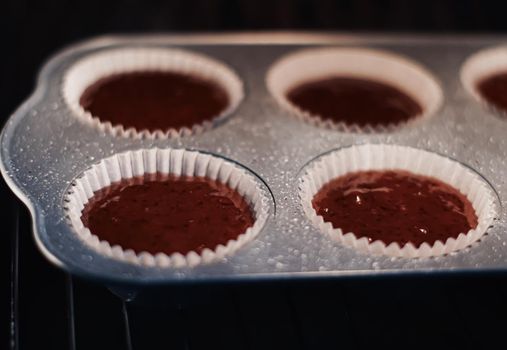 Chocolate muffins baking in the oven, homemade comfort food recipe concept