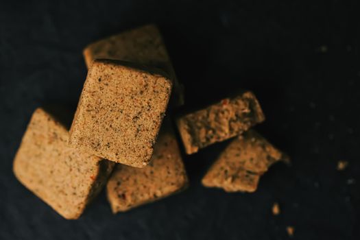 Vegetable bouillon cubes on stone kitchen board, stock or broth ingredient for soup, closeup