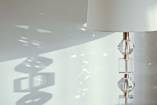 Gold and crystal details of a bedside lamp with shadows at sunset, luxury home decor closeup