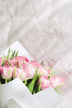 Romantic bouquet of pink tulips on bed in bedroom, holiday gift concept