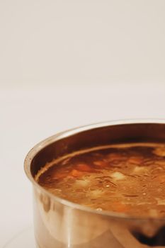 Vegetable soup with beans boiling in a saucepan, homemade food closeup