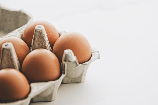 organic eggs in egg box on white marble kitchen table, closeup