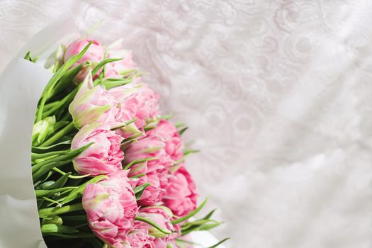 Romantic bouquet of pink tulips on bed in bedroom, holiday gift concept