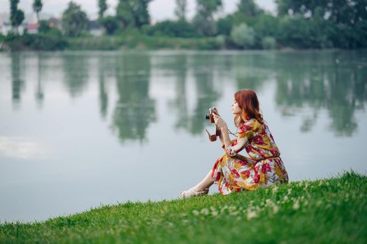 woman outdoors in a dress with a camera in her hands on the shore of the lake vacation. High quality photo