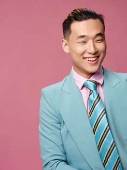 man of Asian appearance blue suit self confidence pink background. High quality photo