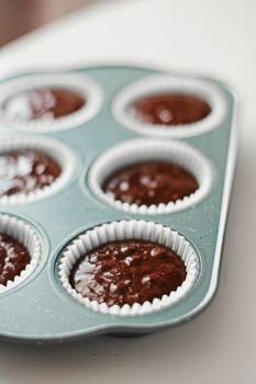 Chocolate muffin or cupcake batter in a pan ready to bake, homemade comfort food recipe concept