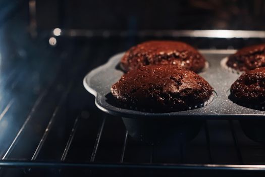 Chocolate muffins baking in the oven, homemade comfort food recipe concept