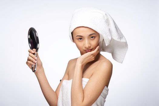 woman with a towel on her head holding a mirror in her hands skin care lifestyle. High quality photo