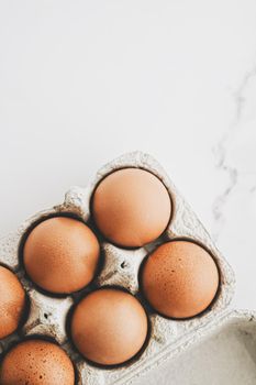 organic eggs in egg box on white marble kitchen table, closeup