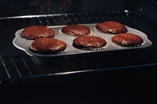 Chocolate muffins baking in the oven, homemade comfort food recipe concept
