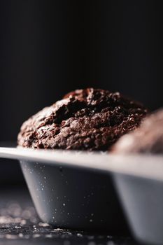 Just baked chocolate muffins in tray, homemade comfort food recipe concept