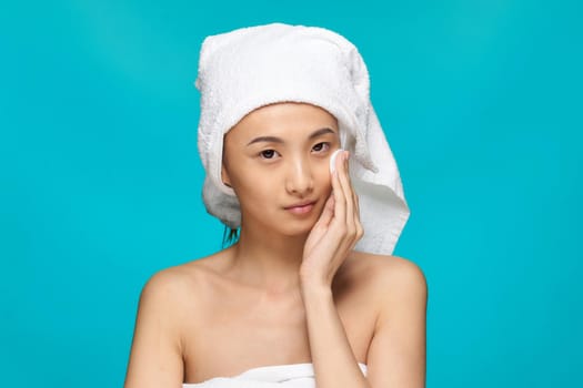 woman with bare shoulders asian appearance clean skin wipes her face after makeup. High quality photo
