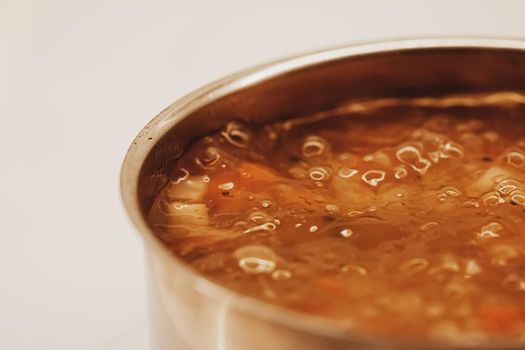 Vegetable soup with beans boiling in a saucepan, homemade food closeup