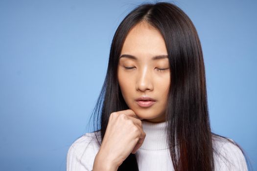 brunette asian touching face with hand makeup model white sweater. High quality photo