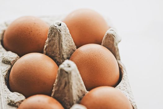 organic eggs in egg box on white marble kitchen table, closeup