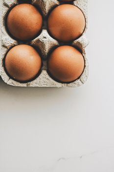 organic eggs in egg box on white marble kitchen table, closeup