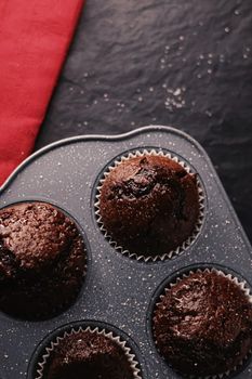 Just baked chocolate muffins in tray, homemade comfort food recipe concept