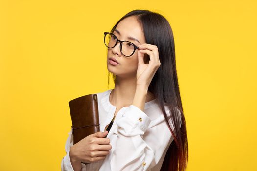 elegant woman holding notepad glasses manager executive yellow background. High quality photo