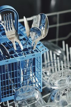 Open dishwasher machine with clean dinnerware in the kitchen, closeup