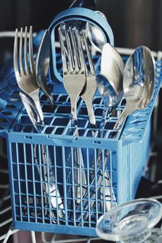 Open dishwasher machine with clean dinnerware in the kitchen, closeup