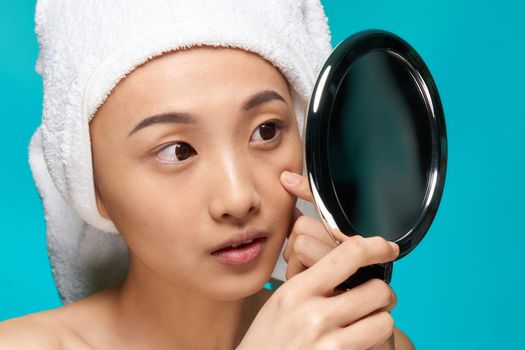 pretty woman naked shoulders towel on head mirror in hands close-up clean skin. High quality photo