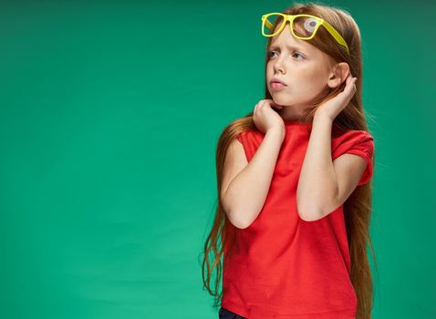 cute red-haired girl with glasses on her head red t-shirt Studio Green background. High quality photo