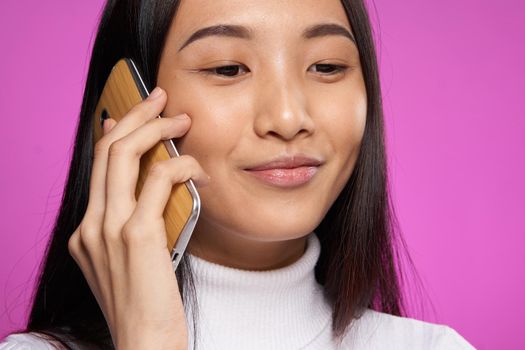 smiling asian woman talking on the phone technology pink background. High quality photo