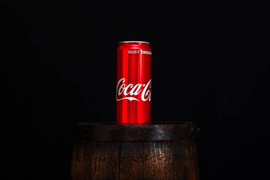 Can of Coca Cola on wooden barrel with dark background. Illustrative editorial photo Bucharest, Romania, 2021