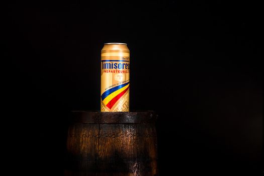 Can of Timisoreana beer on beer barrel with dark background. Illustrative editorial photo shot in Bucharest, Romania, 2021