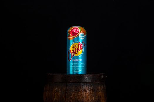 Can of Ursus Cooler beer on beer barrel with dark background. Illustrative editorial photo shot in Bucharest, Romania, 2021