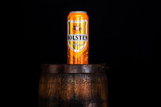 Can of Holsten beer on beer barrel with dark background. Illustrative editorial photo shot in Bucharest, Romania, 2021