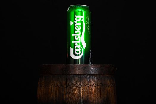 Can of Carsberg beer on beer barrel with dark background. Illustrative editorial photo shot in Bucharest, Romania, 2021