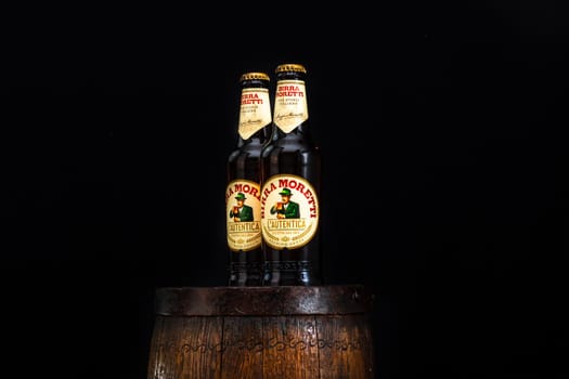 Bottle of Birra Moretti beer on wooden barrel with dark background. Illustrative editorial photo Bucharest, Romania, 2021