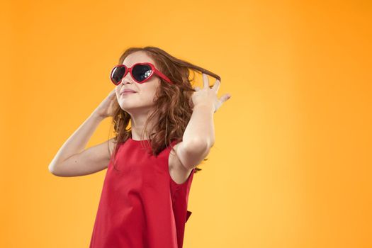 Girl in black glasses red dress childhood fun yellow background. High quality photo