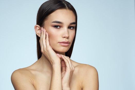 Woman with naked shoulders long hair clean skin cropped view blue background. High quality photo