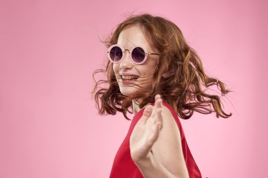 girl with curly hair sunglasses childhood joy pink background. High quality photo