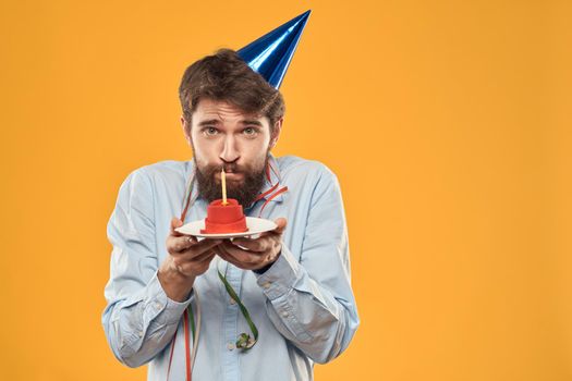 Guy with a cake in a plate on a yellow background holidays candle cropped view. High quality photo