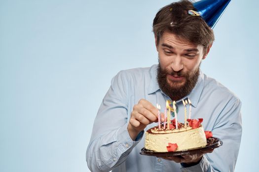A man in a shirt with a cake in his hands and a festive cap on his head. High quality photo