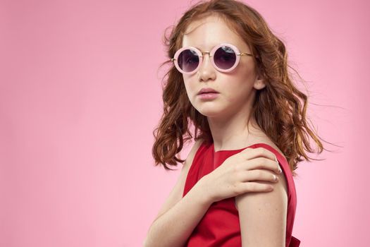 Cheerful little girl childhood dark glasses red dress lifestyle pink background. High quality photo