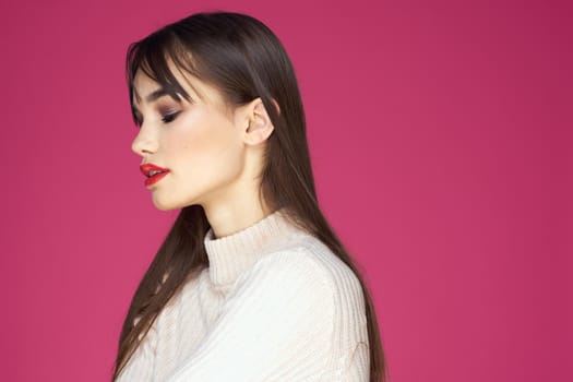 Brunette with long hair red lips cosmetics white sweater pink background cropped view. High quality photo