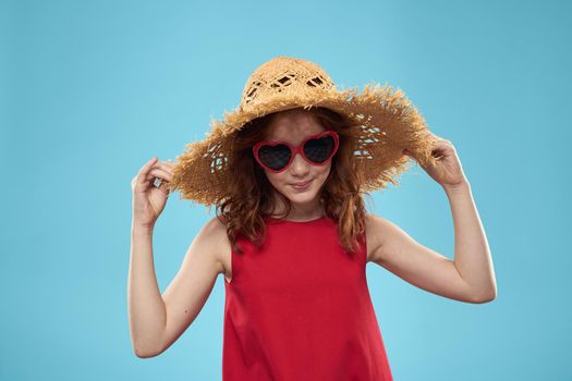 Girl in a beach Straw hat in sunglasses curly hair fun blue background. High quality photo