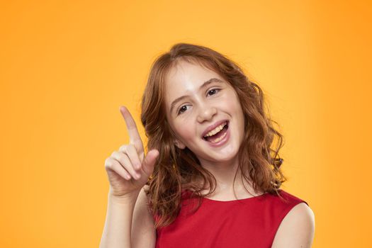 Girl with curly hair red dress fun childhood emotions yellow background. High quality photo