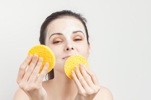 woman with bare shoulders cream mask on face scrub sponges. High quality photo