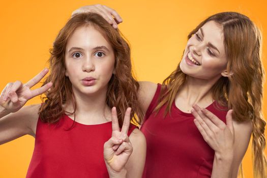 Mom and daughter in red dresses entertainment lifestyle yellow background. High quality photo