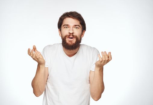 Emotional man with a beard holds his hands near his face on a light background cropped view. High quality photo