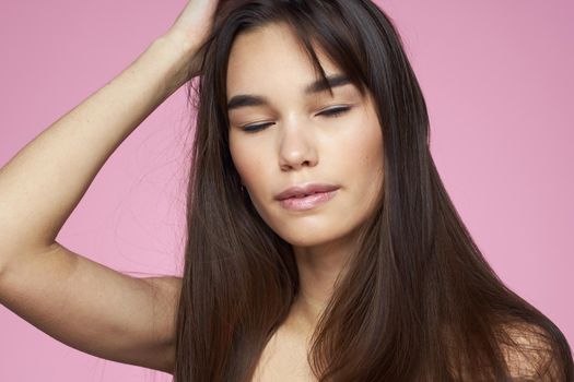 Pretty brunette naked shoulders clear skin pink background. High quality photo
