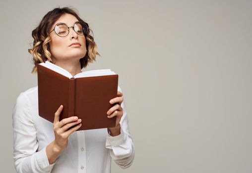 Woman with brown notepad on a gray background and glasses on her face. High quality photo