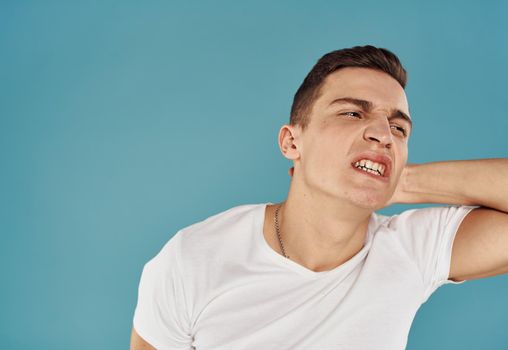 Cute man holds his hand behind his head displeased blue background. High quality photo