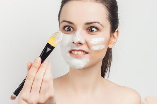 attractive brunette applying mask on face with brush skin care. High quality photo